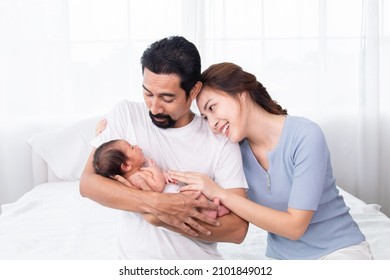 Selective Focus Of Asian Woman And Man Holding Newborn Baby In Bed At Home. Happy Family Smiling With Adorable Infant, Young Parents Holding Little Sweet Toddler Baby, Love And Happiness Concept.