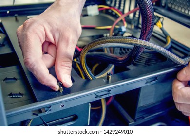 Selective focus. Assembling a personal desktop computer. Installing the power supply in the case, screw tightening. 