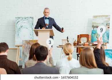 selective focus of auctioneer holding gavel and microphone and looking at buyers during auction - Shutterstock ID 1657604152