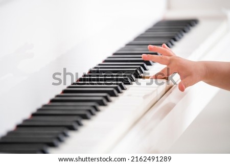 Selective focus to baby fingers and piano key to play the piano. There are musical instrument for concert or learning music. Close up hand of child musician playing the piano on stage.