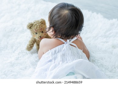 Selective Focus Back Of Adorable Caucasian Little Baby Daughter Kid Girl, Relax Day Sleeping, Crawling, Laying Down Alone, Playing With Blur Background Bear Doll Alone On White Bed At Home