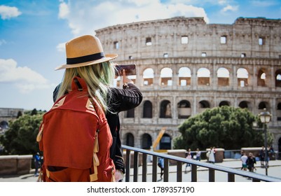 Selective focus of back view asian blogger woman tourist with backpack which she is take a picture by smartphone at Colosseum in Rome, Italy. 