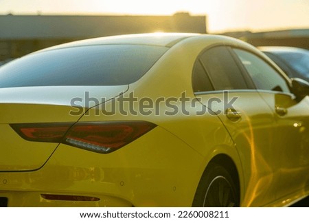A selective focus back view of a bright yellow Mercedes-Benz car driving
