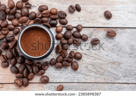 Selective focus, background of coffee beans on an old teak wood table with ground coffee powder in a container