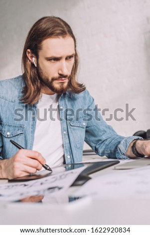 selective focus of bearded of animator in wireless earphones drawing sketches