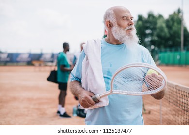 Selective Focus Of Bearded Old Man With Towel And Tennis Racquet On Court