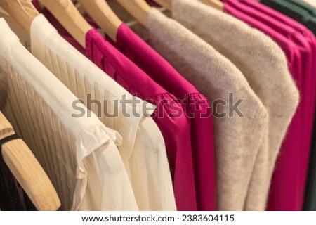 selective focus blouses and sweaters hanging from hangers in a clothing store