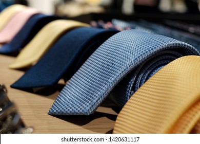 selective focus at blue necktie. Roll up necktie on the table and blur background . Concept of gentleman and necktie fashion, Shopping , father's day.