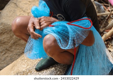 selective focus blue net in the hands of villagers catching fish along the river rapids in Thailand