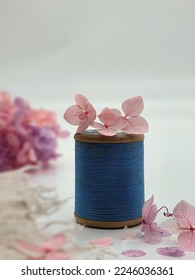Selective focus of blue thread spool with pink flowers on white background