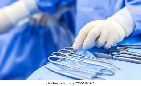 Selective focus with blur background.Nurse team picking up surgical clamps instruments for surgeon inside operating room in modern hospital.Doctor in blue protective uniform doing cosmetic surgery. - Powered by Shutterstock