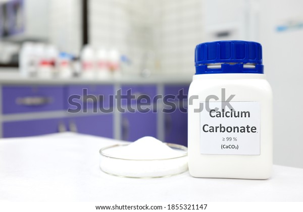 Selective focus of a bottle of calcium carbonate\
chemical compound or soda ash beside a petri dish with solid\
crystalline powder substance. White Chemistry laboratory background\
with copy space.