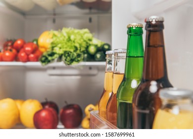 Selective Focus Of Bottles Of Beer On Fridge Door Near Fresh Food On Shelves