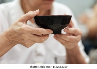 Selective focus at a bowl in elderly hand. Old Asia people holding a bowl and try to eating soup. Concept of culture of Asian eating food. healthcare and elderly people with good health.