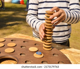 A selective focus of a boy who assembles a turret from the details of a wooden memory game.