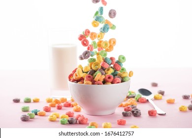 selective focus of bright multicolored breakfast cereal falling in bowl near milk and spoon on white background - Powered by Shutterstock