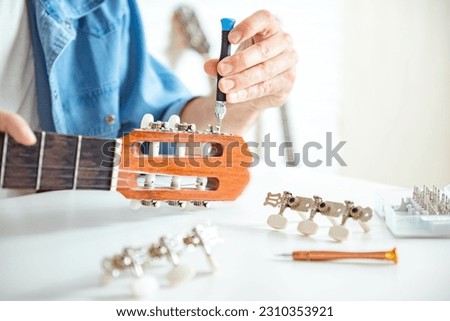 Selective focus to broken guitar with screwdriver to repairing guitar in guitar repair shop. Repair of a musical instrument, replacement of guitar pegs