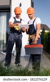 Selective Focus Of Builders With Tool Belt And Toolbox Using Digital Tablet On Urban Street