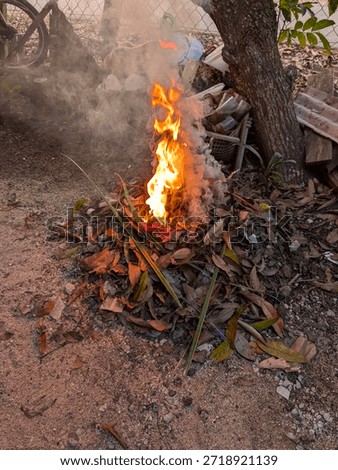 Selective focus of a burning fire, pollution from burning waste at open area, garbage from household, toxic burn trash danger, out of focus, noise and grain effects, enviroment concept.