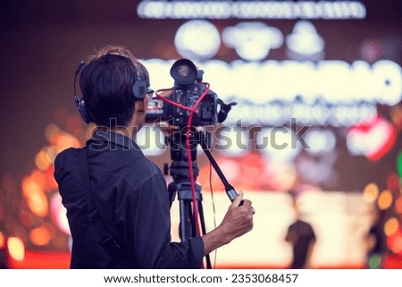 selective focus to cameraman with blurry video camera set are recording to speaker and audience in conference hall or seminar event. exhibition convention center. mass media concept.