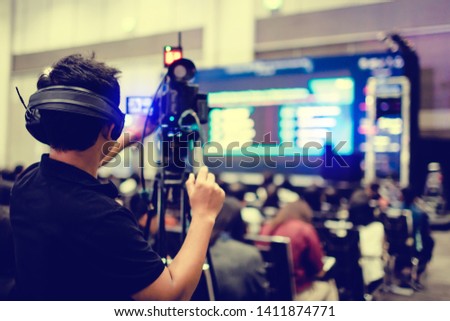 selective focus to cameraman and video camera set are recording to speaker and audience in conference hall or seminar event. exhibition convention center. mass media concept. selective focus.