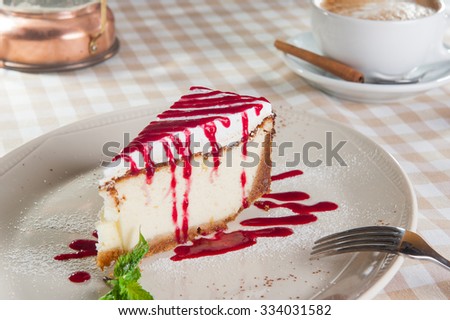 Selective focus Close up Dessert - Cheesecake with berry cream on the white plate decorated with Green Mint on the white plate on the served table with cup of coffee