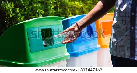 Selective focus close up the man black hand throwing an empty plastic water bottle in the recycling garbage trash or bin, environmental recycling concept 