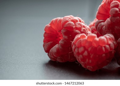 Selective focus and close up view of red and ripe raspberries fruit on black background with copy space