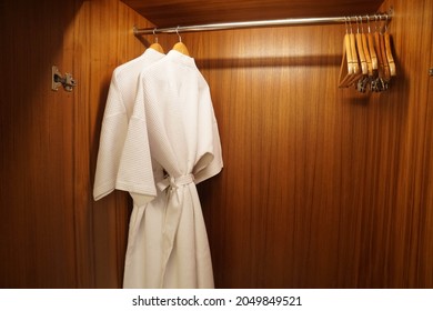 Selective focus close up white two bathrobes in wooden wardrobe for shower in luxury hotel bedroom