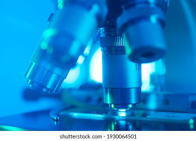 Selective Focus Close-up Of A Labratory Microscope Lens With Slide Against Blue Background