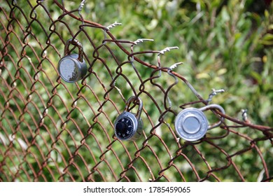 Selective focus close-up view of a lock attached between others to a rusty bridge fence