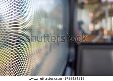Selective focus, close-up view at One Way Vision sticker film with dot pattern on glass of Train's window and blurry background of train's passenger train and bokeh.
