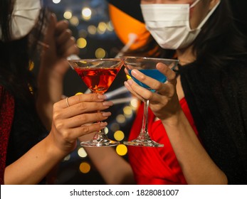 Selective Focus, Colorful Cocktail Glasses Of Two Asian Women In Halloween Costume Wearing Medical Mask During Pandemic Outbreak Of Coronavirus Or Covid-19. New Normal Lifestyle, Halloween Party. 