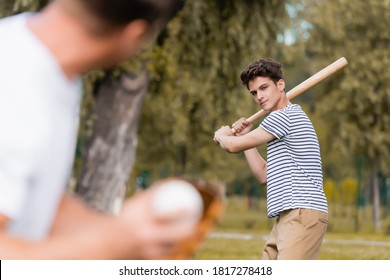 Selective Focus Of Concentrated Teenager Son With Softball Bat Playing Baseball With Father In Park