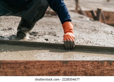 Selective focus, Construction worker leveling concrete floor with trowel. Construction worker pouring cement and concrete.