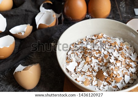 selective focus of cracked eggshells and grinded eggshells on dark stone table