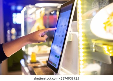Selective focus to customer's hand is touching a touch screen to order food and pay electronically.