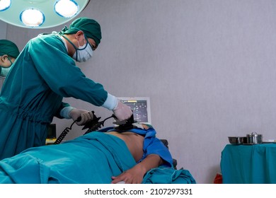 Selective focus at defibrillator while doctor use it to pump at chest of unconscious with low heart rate patient to save life while doing medical surgery inside of operating room. Emergency aid, CPR.