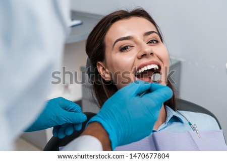 selective focus of dentist in latex gloves holding dental mirror near woman