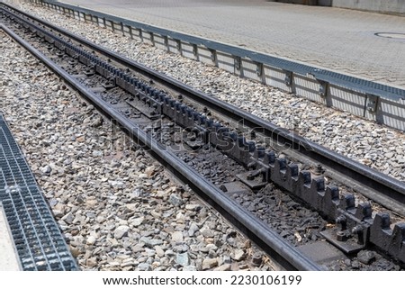 

Selective focus, diagonal view of trail tracks in the Swiss alps. The middle track is known as a cog wheel and help train go up and down mountains. 