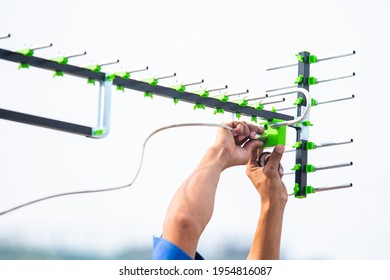 Selective focus to The digital TV antenna with the hands of a technician is installing.