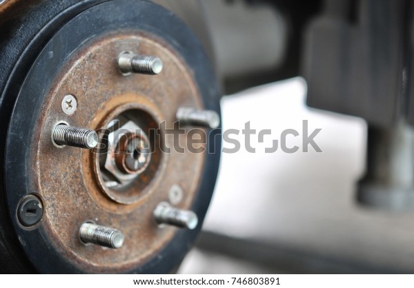 Selective focus disc brake on car, in process of\
new tire replacement,Car brake repairing in garage, Brakes on a car\
with removed wheel, car brake part at garage,car brake disc without\
wheels closeup