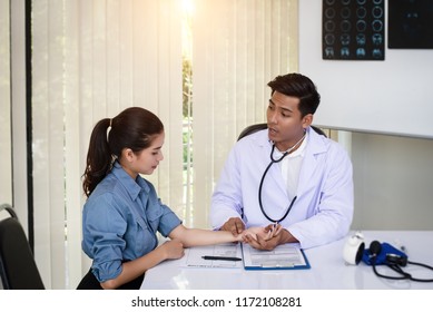 In Selective Focus Of The Doctor Is Checking Heart Rate By Pressing On The Patient Arm,warm Light Tone, Blurry Light Around