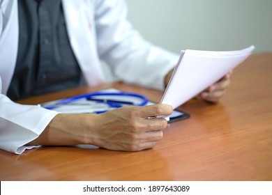 Selective focus of doctor hand  with  a paper of patient are discussing something which the doctor explaining diagnosis to patient in the clinic office-Healthy concept - Shutterstock ID 1897643089