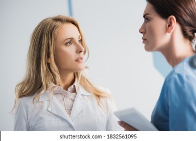 Selective focus of doctor looking at pensive nurse with digital tablet in clinic - Shutterstock ID 1832561095