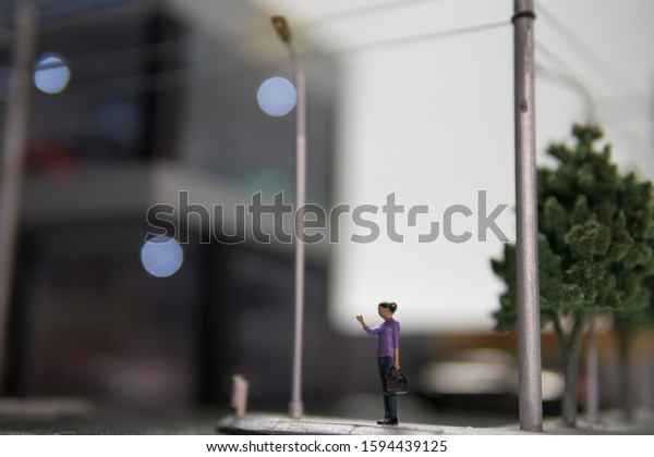 Selective focus of doll figure\
adult woman standing at pedestrian walkway with blurred\
background.