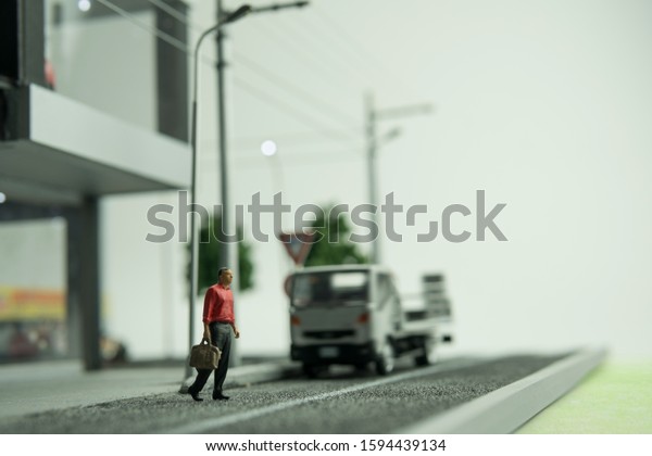 Selective focus of doll\
figure adult man walking across street with blurred background.\
Road safety concept.