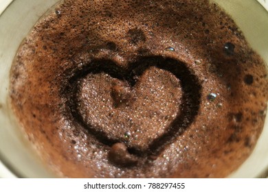 Selective focus of drip pour over ground coffee in filter with a heart drawing on it 