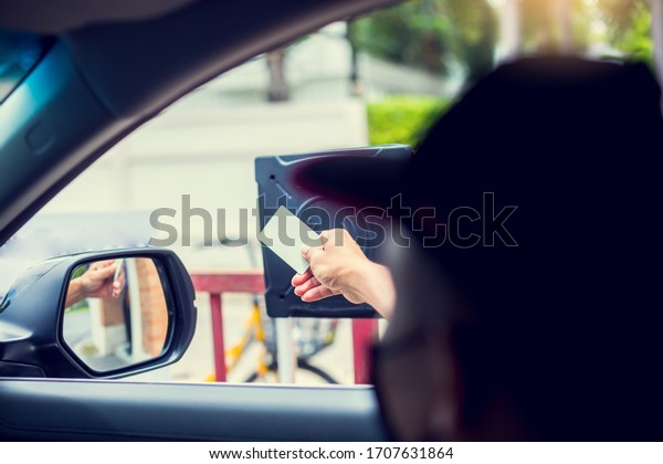 Selective focus to driver hold card to scan at\
card reader station for open the car park door. stop car and use\
key card to open the door for safety. security system for parking.\
The security concept.