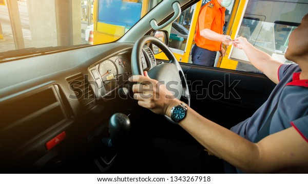 Selective focus to\
driver pay for the expressway, man pays money to a cashier for a\
toll road toll gate motorway entrance, view from inside car image, \
the concept of travel\
expense.